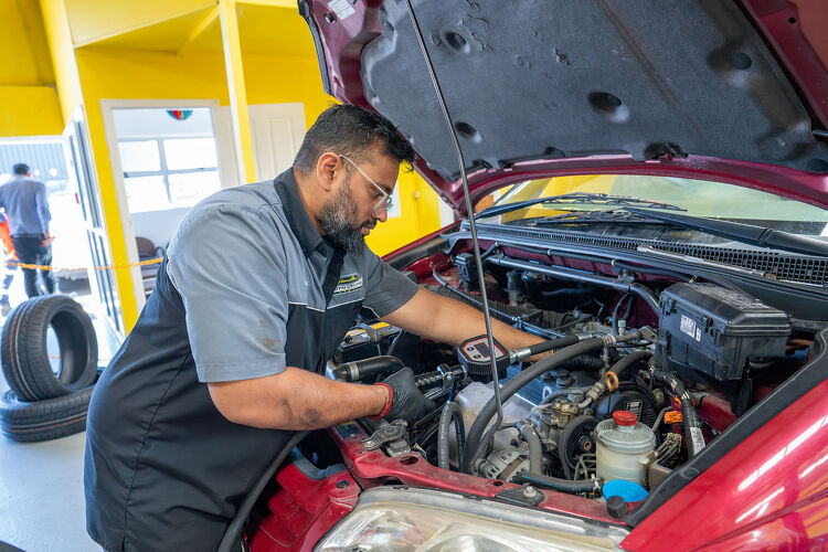Hamilton Auto Centre mechanic servicing the engine of a red car
